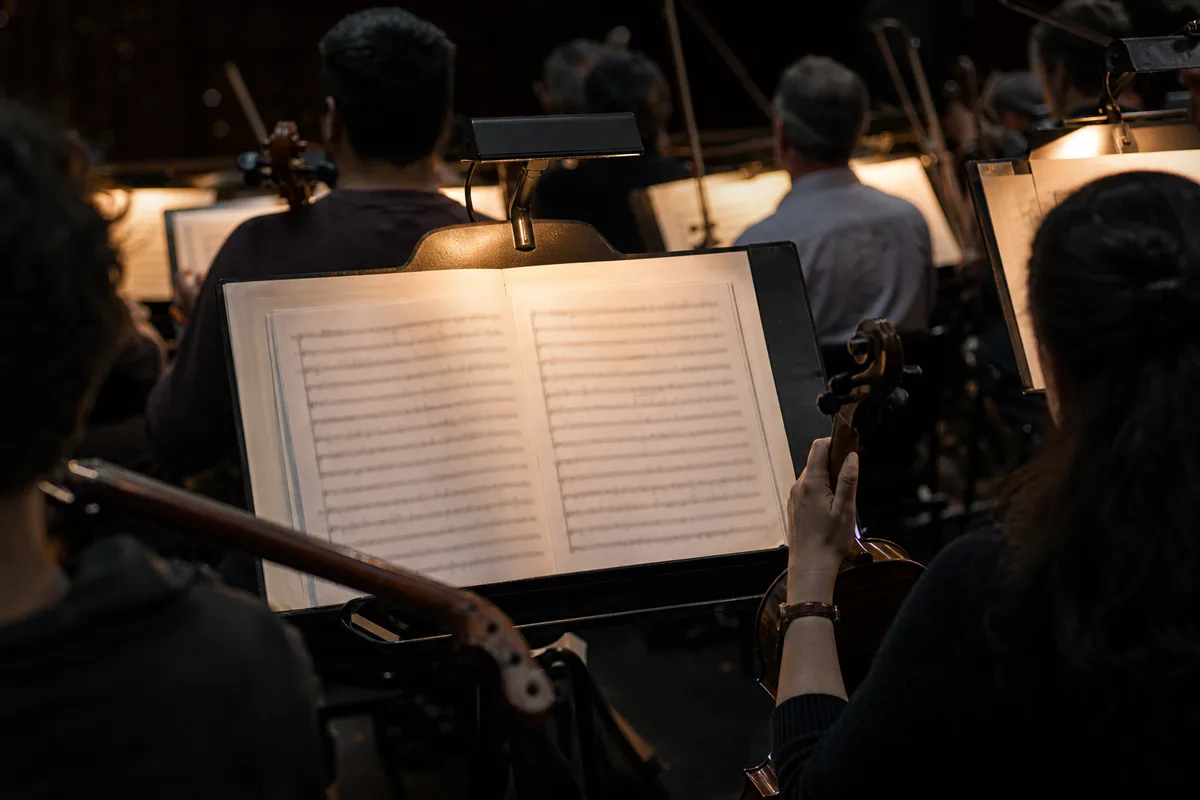 Musiciens de fosse d&rsquo;orchestre en répétition, partitions éclairées par des lampes de pupitre