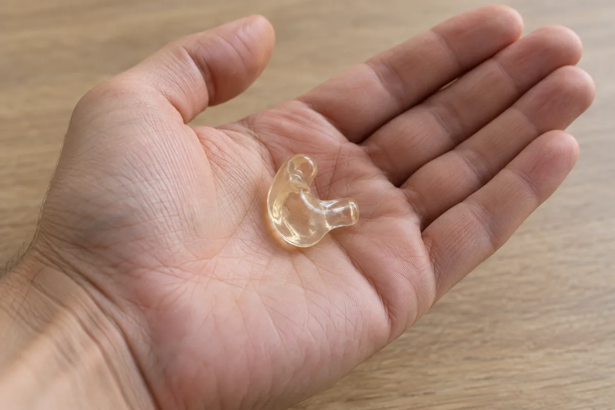 Bouchon d&rsquo;oreille moulé translucide posé dans une paume ouverte