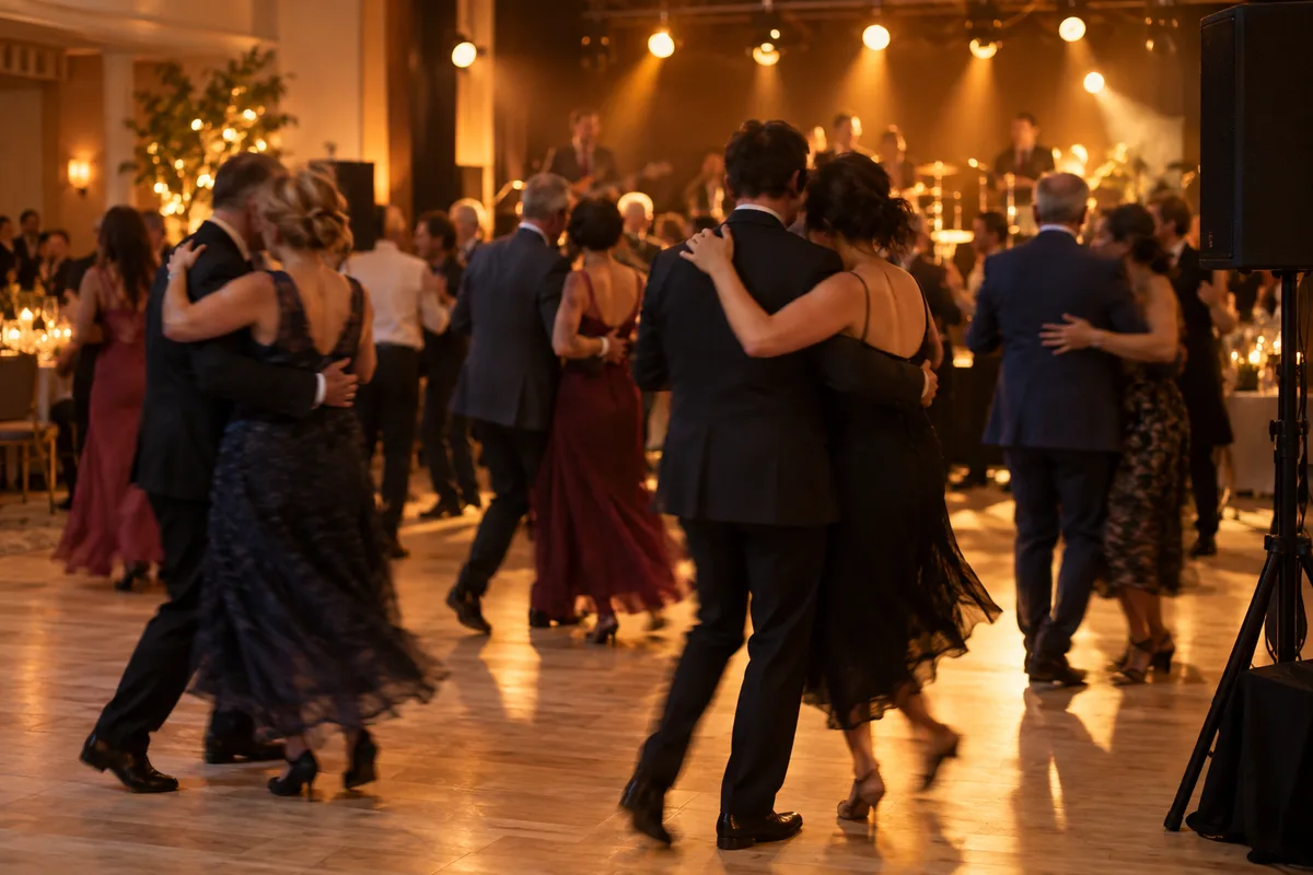 Couples de danseurs vus de dos sur une piste de bal éclairée par des projecteurs chauds